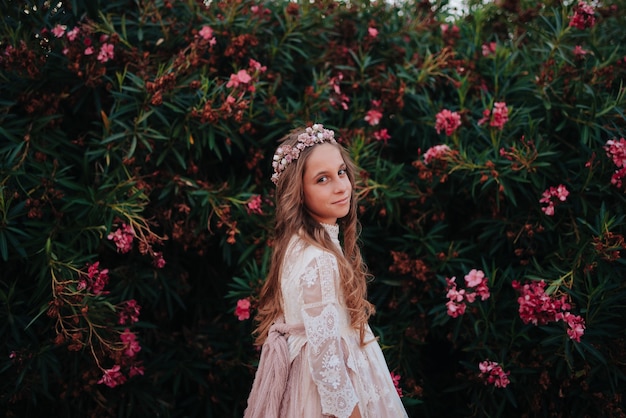 Retrato de una chica rubia con el pelo rizado vestida con traje de comunión sobre un fondo de flores