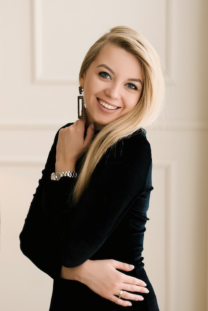 Retrato de una chica rubia sonriente con un vestido negro