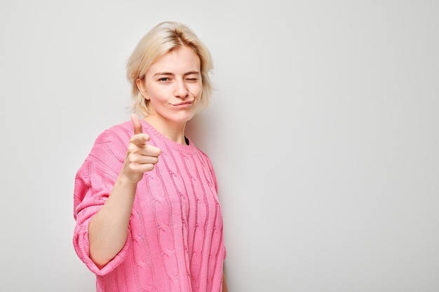 Retrato de una chica segura de sí misma te elige apuntando con el dedo a la cámara aislada en el fondo blanco del estudio Gesto de bienvenida únete a nuestro concepto de equipo