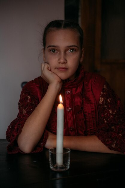 Retrato de una chica sentada junto a una vela en la mesa