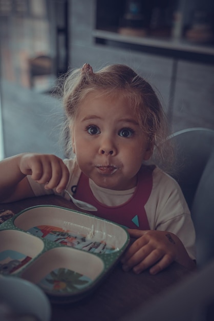 Retrato de una chica sentada en la mesa y comiendo