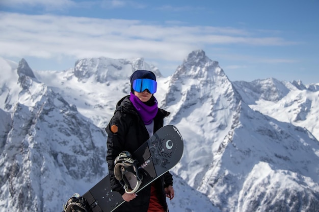 Retrato de una chica con snowboard en la cima de una montaña nevada.