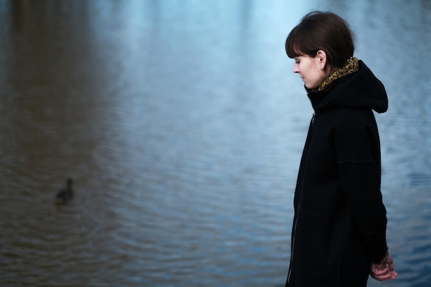 Retrato de una chica solitaria junto al lago Se pone de pie con ropa negra y mira tristemente a un lado Pienso en lo triste