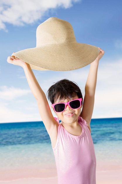 Retrato de una chica con un sombrero mientras está de pie en la playa contra el cielo