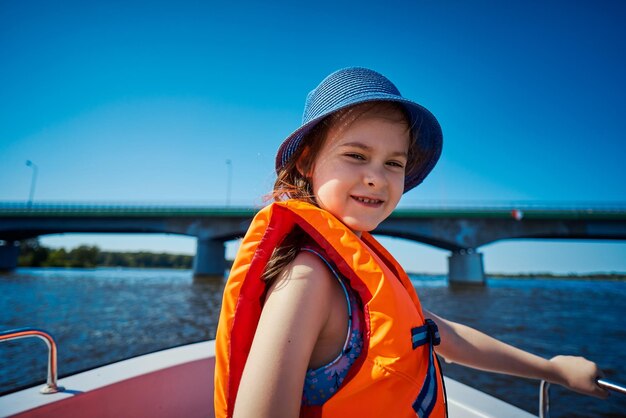 Retrato de una chica sonriente con chaleco salvavidas de pie en un barco