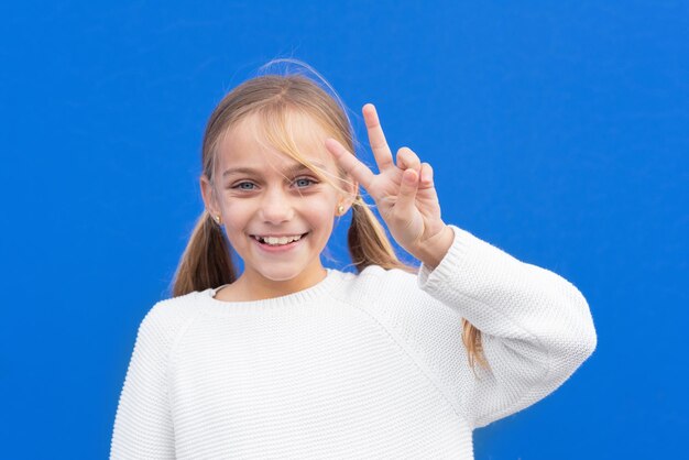 Foto retrato de una chica sonriente de pie contra el cielo azul