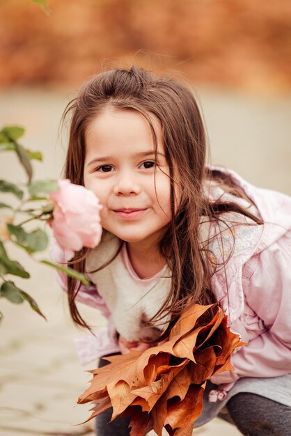 Foto retrato de una chica sonriente por una planta de rosa