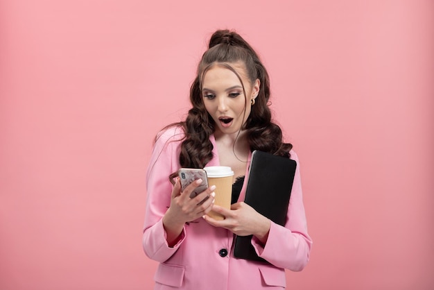 Retrato de una chica sorprendida y desconcertada con una chaqueta leyendo una publicación en un sitio de redes sociales usando el teléfono