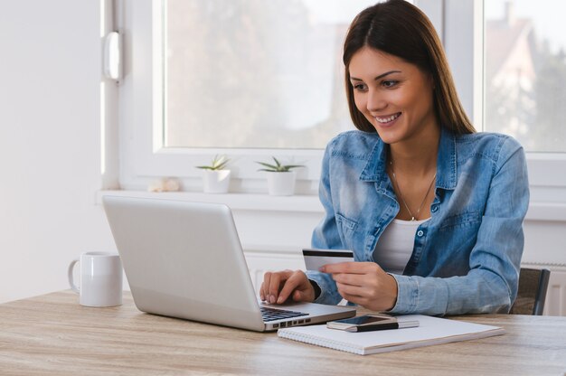 Retrato de una chica con tarjeta de crédito y usando laptop