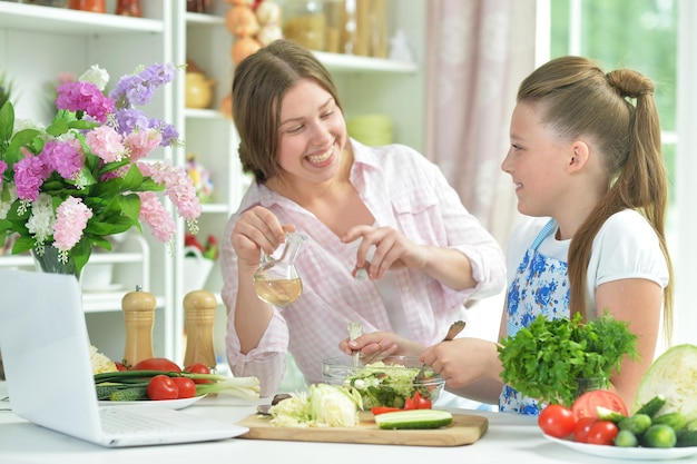 Retrato de chicas divertidas preparando ensalada fresca