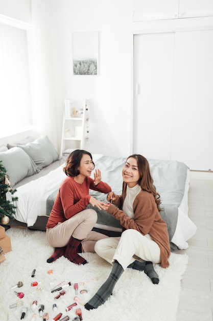 Foto retrato de chicas guapas pintando uñas en casa