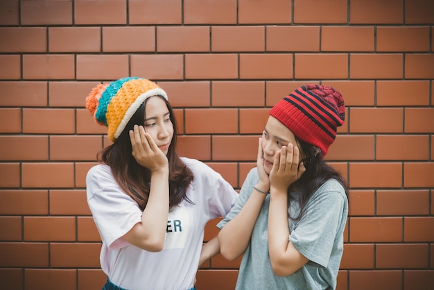 Retrato de chicas hipster asiáticas sobre fondo de pared de ladrillo Estilo de vestir hippie Estilo de vida de mujer moderna de Tailandia Retrato de moda de belleza al aire libre