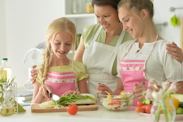 Retrato de chicas lindas con madre cocinando en la cocina