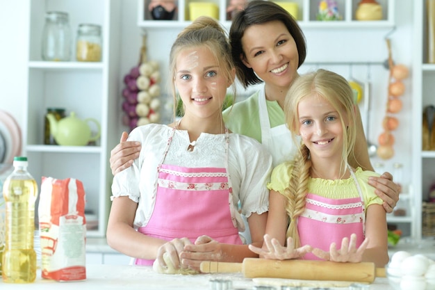 Retrato de chicas lindas y madre horneando en la cocina en casa