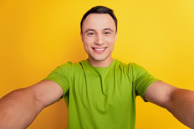 Retrato de chico alegre positivo mantenga la cámara tomar selfie sobre fondo amarillo