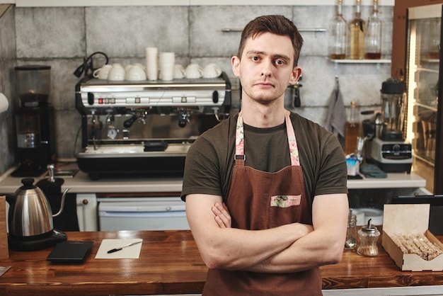 El retrato del chico baristas en el lugar de trabajo sobre fondo de café