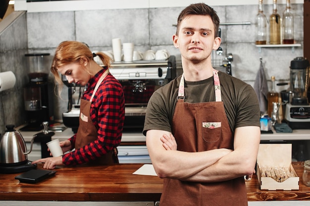 El retrato del chico baristas en el lugar de trabajo sobre fondo de café