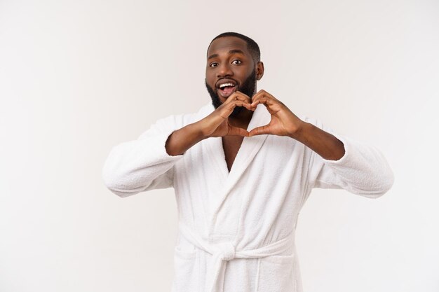 Retrato de un chico creativo, romántico, positivo, alegre y confiado que hace el símbolo del amor con la figura del corazón con los dedos mirando a la cámara aislada en el fondo gris