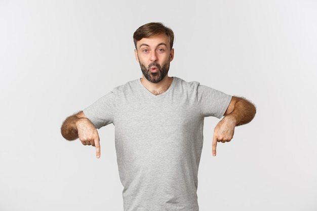 Retrato de chico emocionado con barba, señalando con el dedo algo curioso