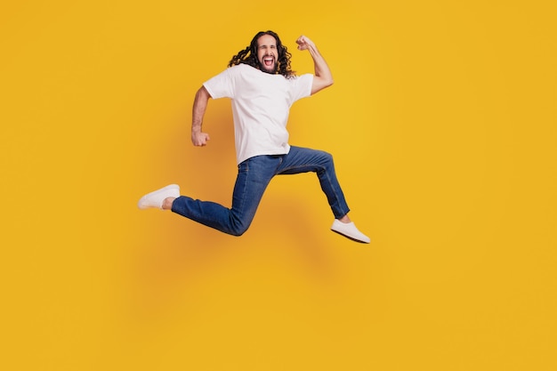 Retrato de chico enérgico deportivo ejecutar salto emocionado sobre fondo amarillo