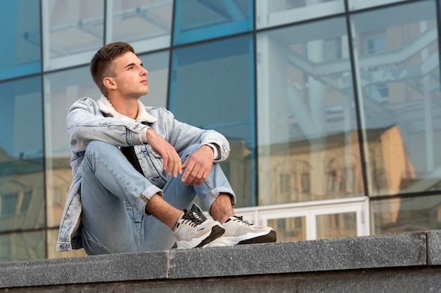 Retrato de un chico estudiante en ropa casual. Apuesto joven descansando en la calle. Estudiante esperando a su novia.