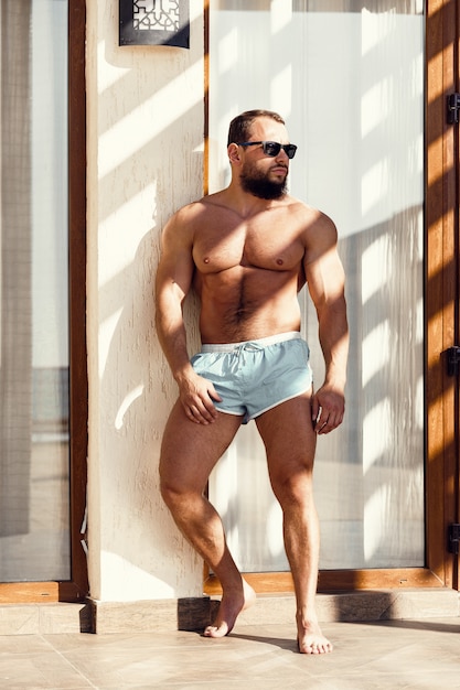 Retrato de un chico guapo en traje de baño y gafas de sol