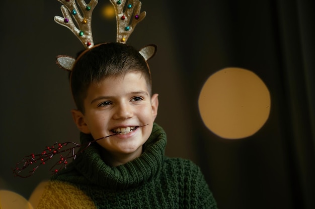 Retrato de un chico lindo alegre con cuernos de ciervo para Navidad