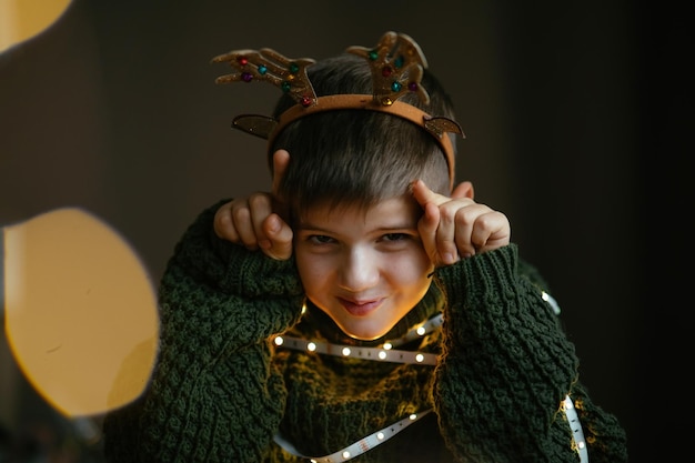 Retrato de un chico lindo alegre con cuernos de ciervo para Navidad