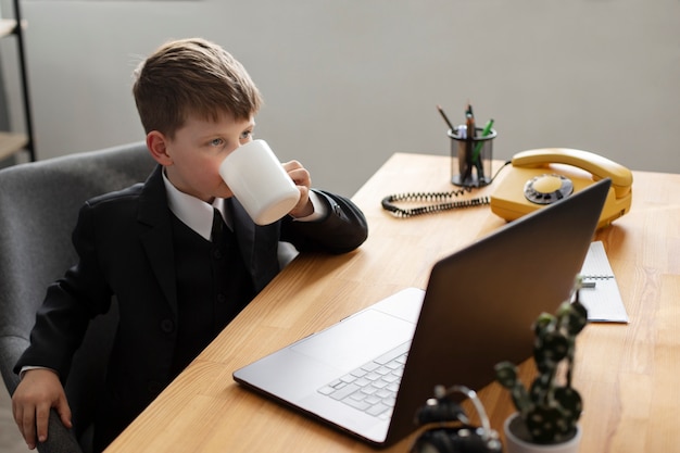 Retrato de un chico lindo con traje tomando un café en su escritorio de oficina