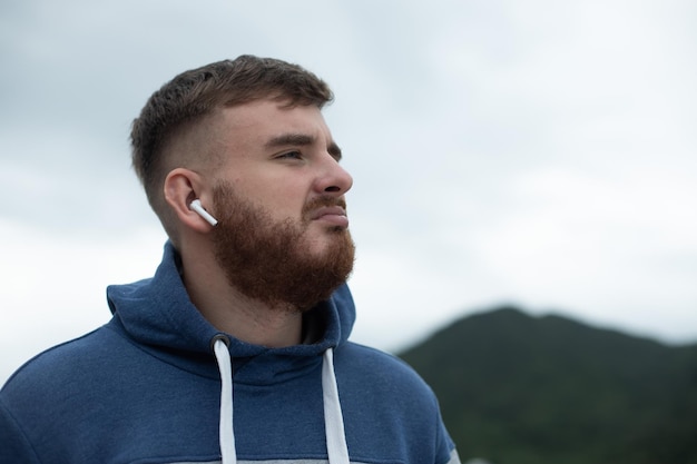 Retrato de chico pensativo pensativo guapo barbudo escuchar música en auriculares joven molesto triste