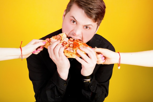 Retrato de un chico con una pizza en un espacio amarillo