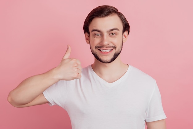 Retrato de chico promotor confiable levantar el pulgar hacia arriba sobre fondo rosa