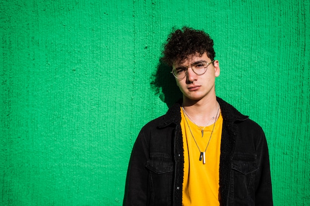 Retrato de un chico vestido moderno en la calle con gafas de sol.