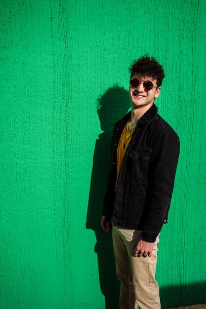 Retrato de un chico vestido moderno en la calle con gafas de sol.