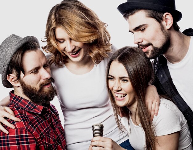 Retrato de chicos y chicas felices cantando en el micrófono sobre fondo blanco.