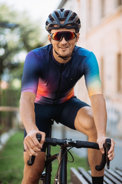 Retrato de ciclista caucásico sonriente en ropa deportiva casco y gafas sentado en bicicleta al aire libre Día soleado y cálido al aire libre Concepto de entrenamiento activo