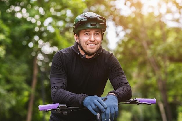 Retrato de ciclista feliz apoyado en el manillar con descanso