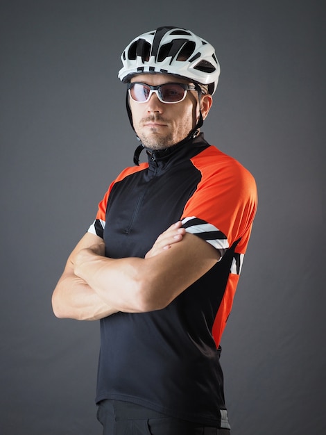 Retrato de ciclista con las manos cruzadas en el pecho con casco blanco y camiseta deportiva.