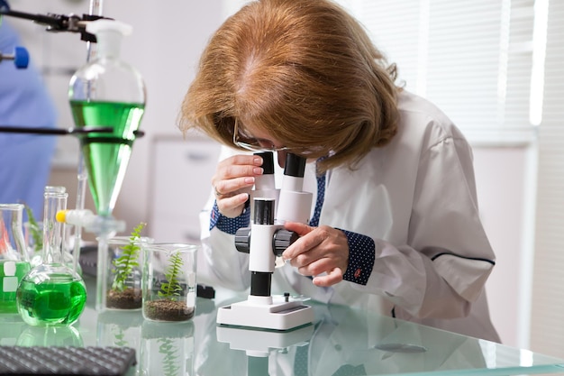 Retrato de una científica de biotecnología de mediana edad que trabaja en un microscopio. Prueba científica.