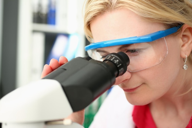 Retrato de una científica enfocada mirando a través del microscopio en el laboratorio