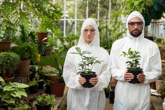 Retrato de científicos en traje limpio con plantas en maceta