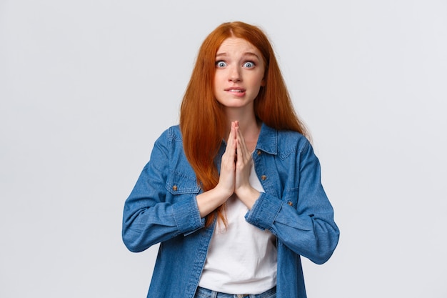 Retrato de cintura alta pelirroja nerviosa estudiante necesita ayuda lo antes posible, mantenga las manos sobre el pecho juntas en oración, sonriendo preocupada e impaciente, suplicando, rogando favor