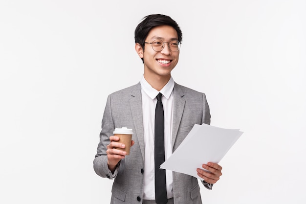 Retrato en la cintura del apuesto hombre de negocios sonriente asiático en traje gris y gafas