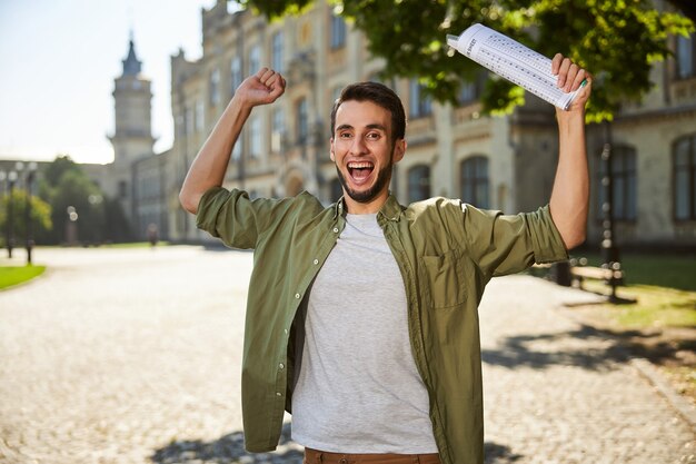 Retrato de cintura para arriba de un estudiante con una hoja de respuestas en la mano posando para la cámara