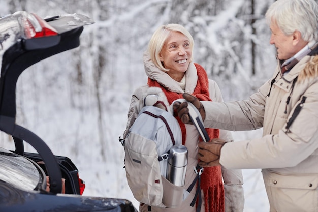 Retrato en la cintura de una pareja senior sonriente sacando una mochila de senderismo mientras disfruta de una escapada de invierno