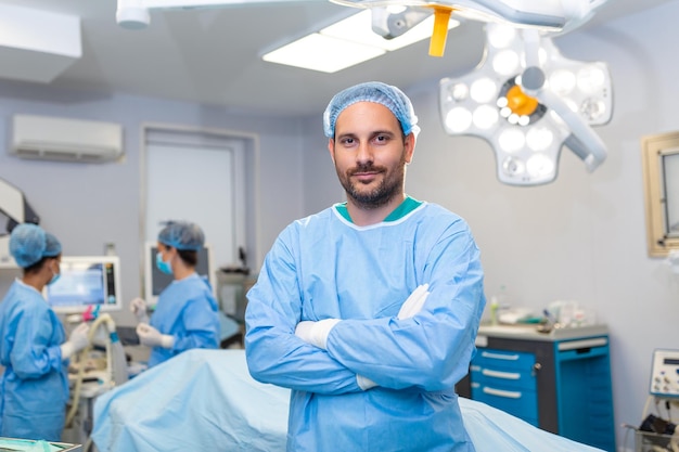 Retrato de un cirujano masculino de pie con los brazos cruzados en el quirófano del hospital Los cirujanos del equipo están realizando una operación El médico de mediana edad está mirando la cámara en un quirófano moderno