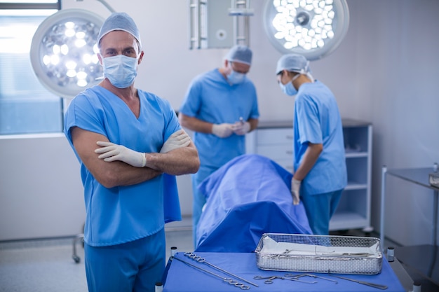 Retrato de cirujano de pie con los brazos cruzados en la sala de operaciones