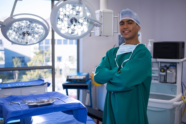 Retrato de cirujano de pie con los brazos cruzados en la sala de operaciones