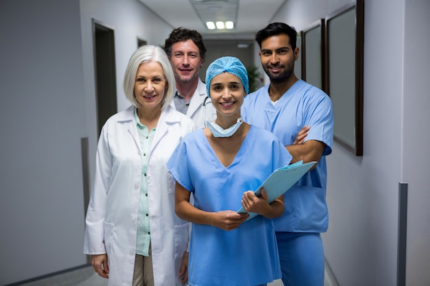 Retrato de cirujanos sonrientes y médico de pie en el pasillo