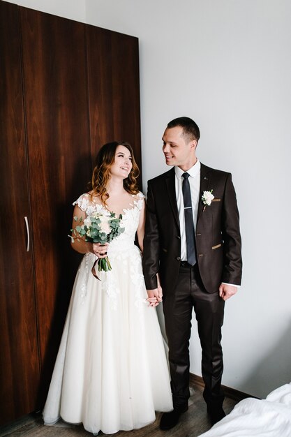 Retrato clásico de los novios de la habitación. Pareja joven feliz día. El concepto de vacaciones y amor en la familia. Día de la boda.